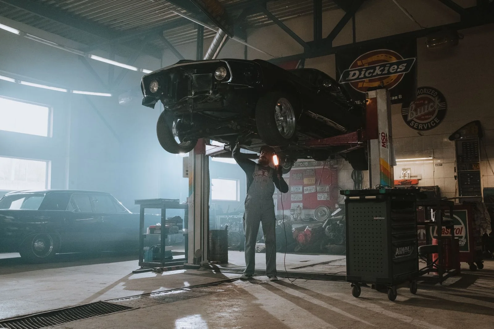 Technician inspecting the underside of a classic car on a lift